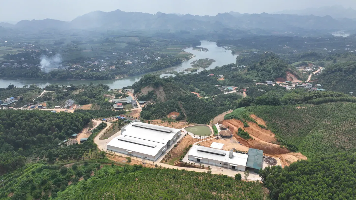 Nhà máy nhìn từ trên cao, bên cạnh dòng sông và đồi núi Yên Sơn